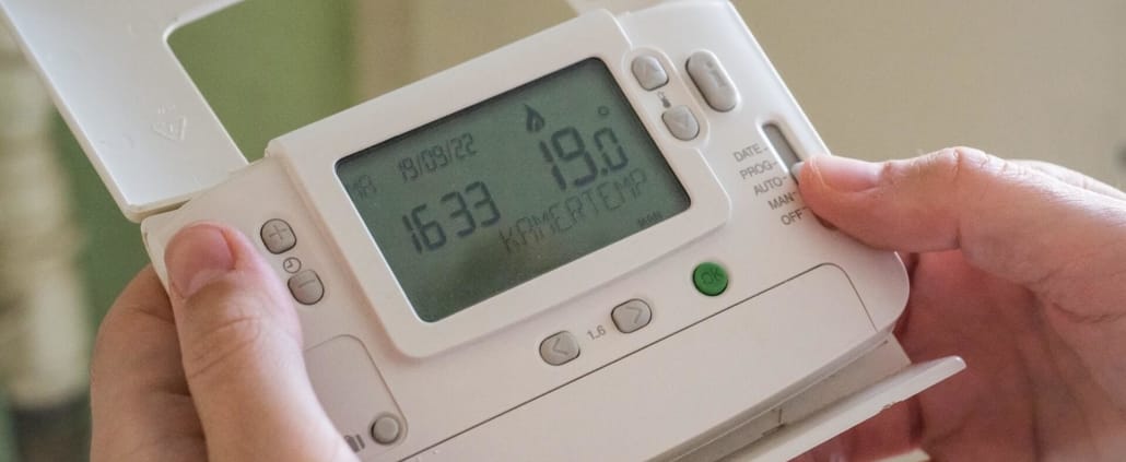 A person holding their thermostat control examining it for any HVAC myths.