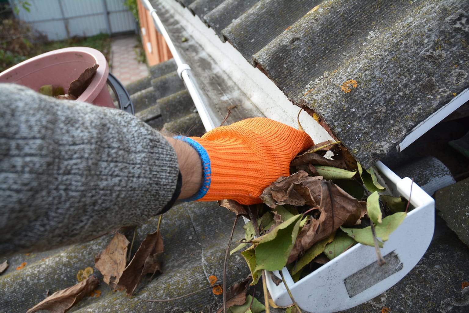 Rain Gutter Cleaning from leaves in autumn with hand. Roof gutter cleaning. Cleaning Gutters with pressure washing tools