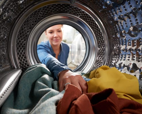 View Looking Out From Inside Dryer Machine As Young Woman Does Laundry