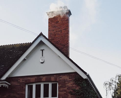 A smoking chimney on top of a residential house in northern virginia that would need chimney cleaning in different seasons.