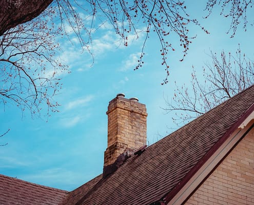 A Chimney with ciimney damage on top of a house