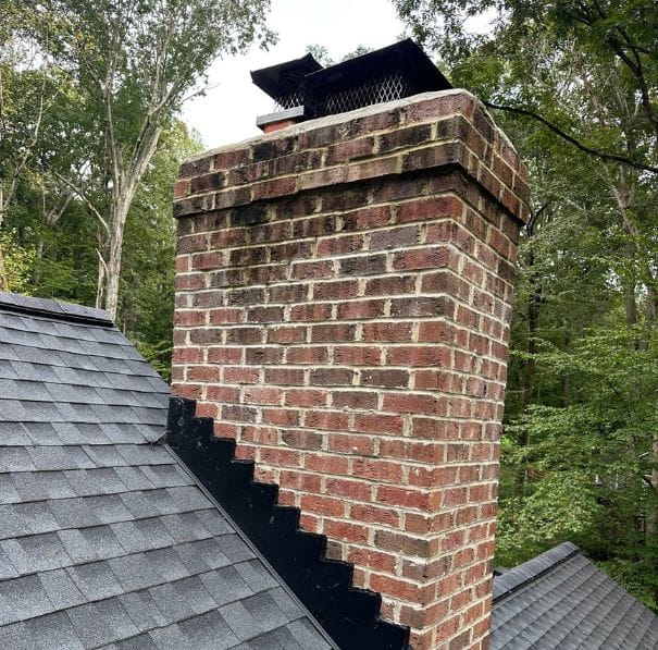 chimney repair services near me woodbridge va Brick chimney with metal cap on sloped roof; fall trees, Woodbridge, VA; chimney repair needed