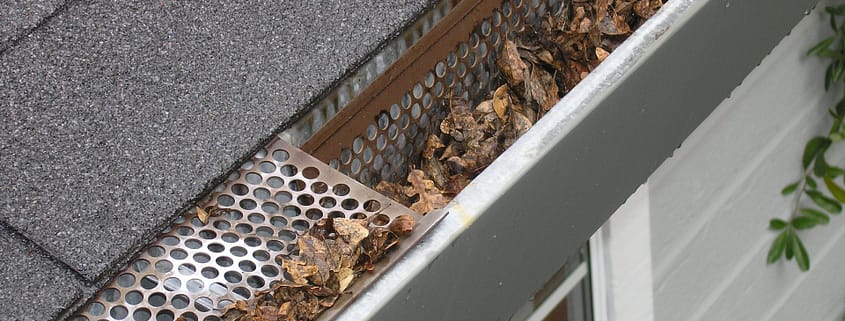 A dirty, clogged gutter causing home problems as a result of not cleaning gutters regularly.